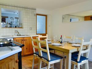 een keuken met een houten tafel met stoelen en een wastafel bij Footdee Cottage in Aberdeen