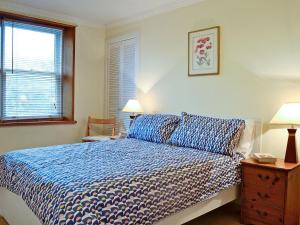 een slaapkamer met een bed, 2 lampen en een raam bij Footdee Cottage in Aberdeen