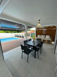 een patio met een tafel en stoelen en een zwembad bij NOUVEAU Villa Ricololo Piscine Balnéo Golf Yoga in Saint-François