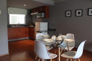 a dining room with a glass table and white chairs at Residence L´ Heritage Hipólito Taine by BlueBay in Mexico City