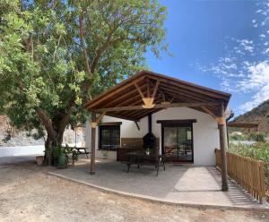 um pavilhão com uma mesa e um banco em frente a uma casa em Casa Rural Las Angosturas (Caminito del Rey) em El Chorro