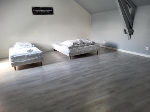 Location 30 personnes : سريرين في غرفة بيضاء مع أرضيات خشبية