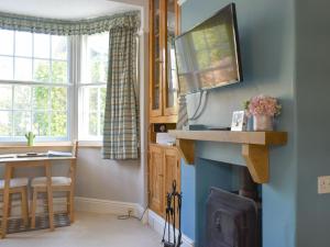 a living room with a television and a fireplace at Beech Cottage in Scalby