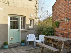 een patio met een tafel, 2 stoelen en een deur bij Beech Cottage in Scalby