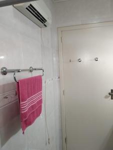 Un baño con una toalla rosa en un toallero. en Cantinho da Tete, en São Francisco de Paula