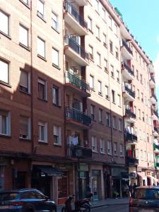 un grand bâtiment en briques avec des voitures garées devant lui dans l'établissement Habitación 1 con vistas, à Bilbao