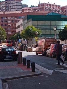 a man crossing a street in a city with cars at Habitación 1 con vistas in Bilbao