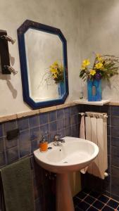 La salle de bains est pourvue d'un lavabo, d'un miroir et de fleurs. dans l'établissement Casa Rosi - Loft tra i monti di Roccaraso, à Rionero Sannitico