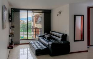 um sofá de couro preto numa sala de estar com uma grande janela em EXPECTACULAR APARTAMENTO OPORTUNOx em Bogotá