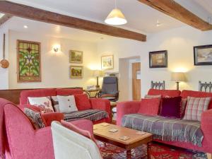 a living room with red couches and a table at Cam Cottage in Kettlewell