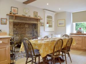 a dining room with a table and chairs and a fireplace at Cam Cottage in Kettlewell