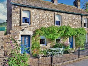 ein altes Steingebäude mit einem Tisch davor in der Unterkunft Cam Cottage in Kettlewell