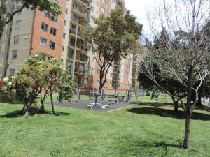 un parque con árboles y un parque infantil frente a un edificio en EXPECTACULAR APARTAMENTO OPORTUNOx, en Bogotá