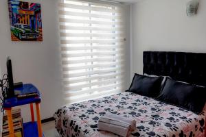 波哥大的住宿－EXPECTACULAR APARTAMENTO OPORTUNOx，一间卧室配有一张床和一个带百叶窗的窗户