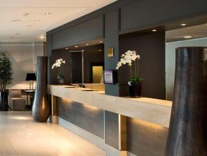 a lobby with a reception counter with white flowers at Park Hotel Hamburg Arena in Hamburg