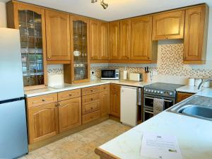 uma cozinha com armários de madeira e electrodomésticos brancos em The Paddock em Bodelwyddan