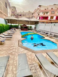 a large swimming pool with chairs and a man in the background at Shady Hotel Luxor in Luxor