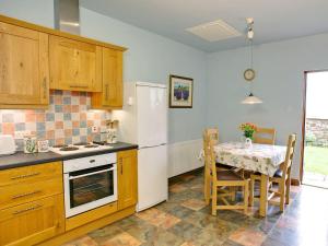a kitchen with a table and a white refrigerator at The Bothy in Haywood