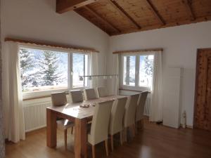 ein Esszimmer mit einem Tisch, Stühlen und Fenstern in der Unterkunft Chalet Crestannes in Davos