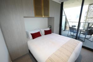 a bedroom with a large white bed with red pillows at Realm Apartments by CLLIX in Adelaide