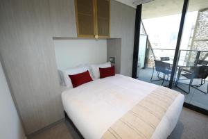 Un dormitorio con una gran cama blanca con almohadas rojas. en Realm Apartments by CLLIX, en Adelaida 80 fotos más
