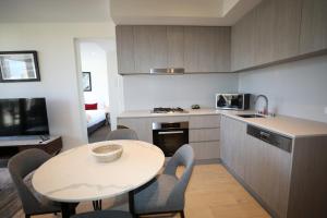 uma cozinha com uma mesa e uma mesa e cadeiras em Realm Apartments by CLLIX em Adelaide