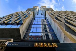 a tall building with a sign in front of it at Realm Apartments by CLLIX in Adelaide