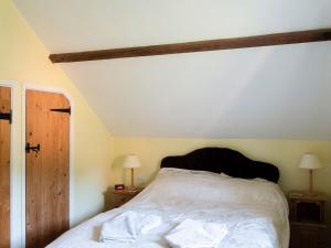 um quarto com uma cama branca, 2 mesas de cabeceira e 2 candeeiros. em The Small Barn em Wood Norton