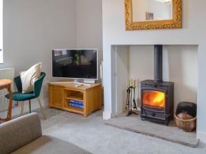 uma sala de estar com lareira e televisão em Old Reading Room em Cotehill