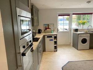 a kitchen with a sink and a washer and dryer at Rosebank Cottage in Aldbrough