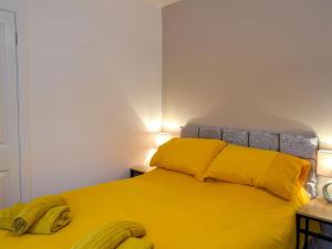 East Lodge في Creebridge: غرفة نوم بسرير اصفر وعليها موزين