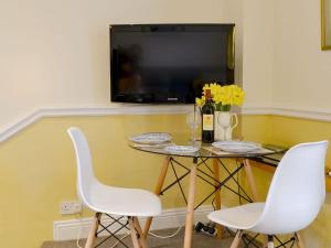 mesa pequeña con 2 sillas blancas y TV en Garth Cottage, en Near Sawrey