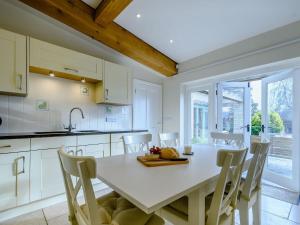 cocina con mesa blanca y sillas en Coach House Cottage en Wotton under Edge