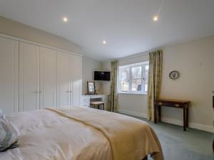 Schlafzimmer mit einem Bett, einem Schreibtisch und einem Fenster in der Unterkunft Coach House Cottage in Wotton under Edge