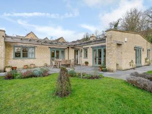 a brick house with a patio and a yard at Coach House Cottage in Wotton-under-Edge