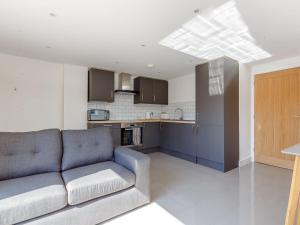 a living room with a couch and a kitchen at Blackberry Cottage in Stowmarket