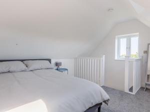 a white bedroom with a large bed and a window at Blackberry Cottage in Stowmarket