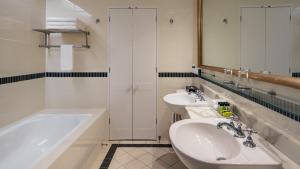 a bathroom with two sinks and a tub and a mirror at InterContinental Sanctuary Cove Resort, an IHG Hotel in Gold Coast