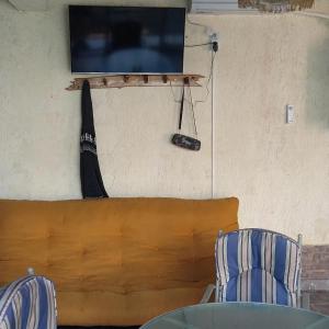 a tv hanging on a wall with a table and two chairs at EDU`S HOUSE IIi in Guaymallen