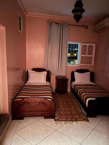 two beds sitting in a room with a window at Ighbola Ouzoud in Ouzoud