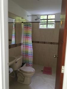 een badkamer met een toilet en een douchegordijn bij GRANJA CAMPESTRE EN CONDOMINIO EL GUAMO-TOLIMA in Guamo