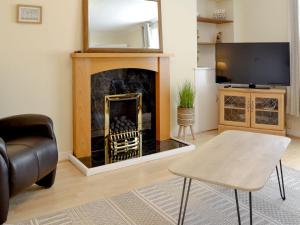 a living room with a fireplace and a tv at Arthurs Cottage in Edzell