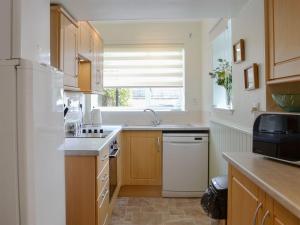 eine Küche mit einem weißen Kühlschrank und einer Spüle in der Unterkunft Arthurs Cottage in Edzell
