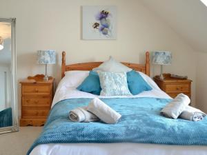 a bedroom with a blue and white bed with towels on it at Arthurs Cottage in Edzell