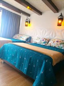 two beds in a bedroom with blue sheets and pillows at Villa Suite Emanuel in Bogotá