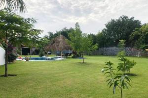 een tuin met een zwembad en een grashut bij Casa Ticumán, villa campestre cerca de Las Estacas in Ticumán