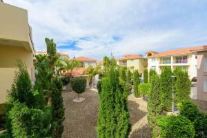 a garden with trees and bushes in front of a building at Great Kings Resorts in Protaras