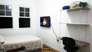 1 dormitorio con 1 cama y TV en la pared en Sobrado Tranquilo Centro en Porto Alegre