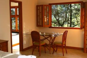 a dining room with a table and four chairs at Pousada Chalé da Floresta in Monte Verde +22 photos