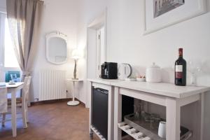 a white kitchen with a counter with a bottle of wine at And So in Lecce